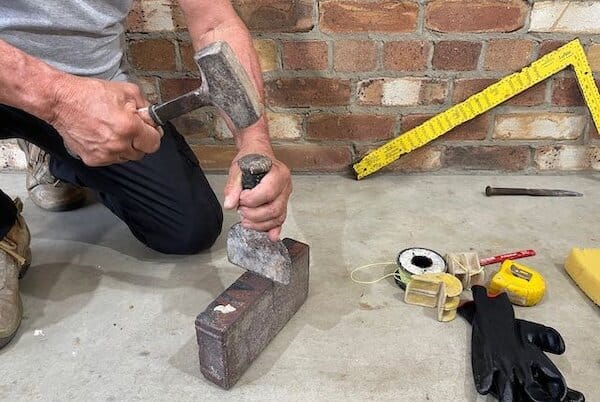 Marty demonstrating brick cutting technique with lump hammer and bolster